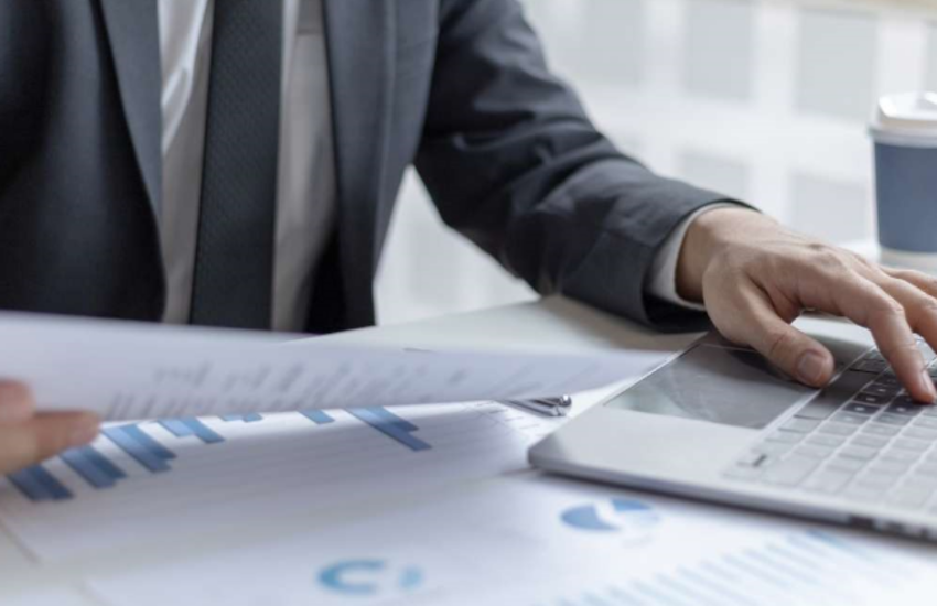 Man in suit working with a laptop and paperwork